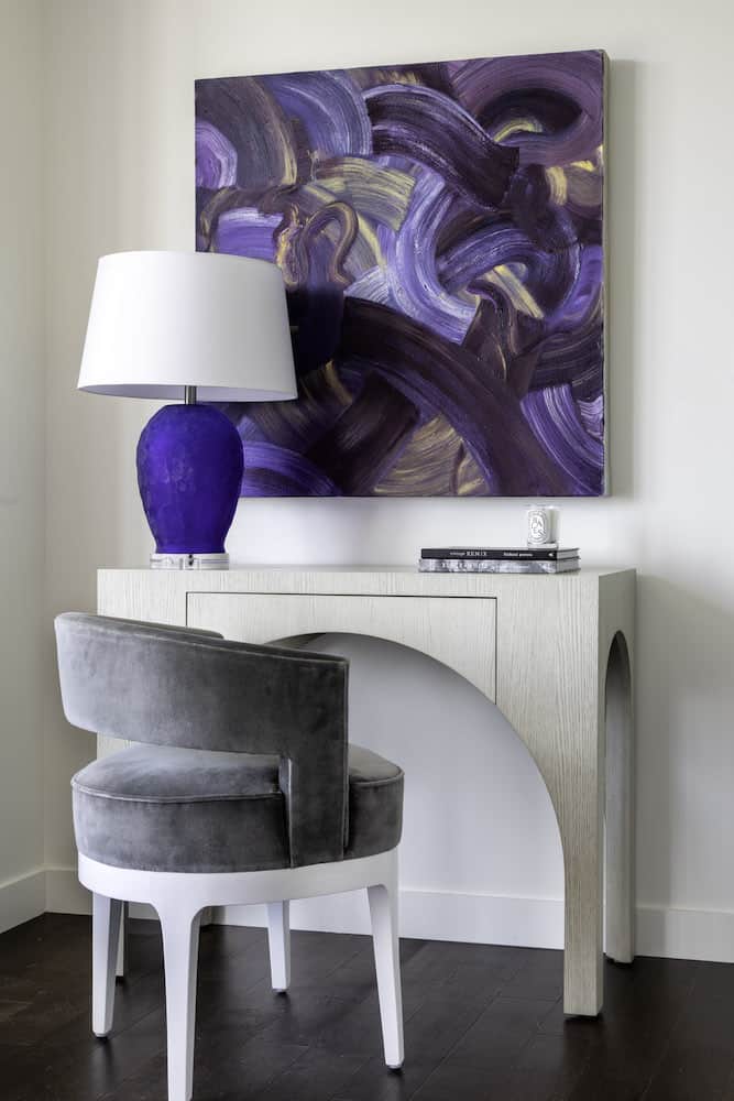 Modern curved paired with gray velvet desk chair and comttemporary art