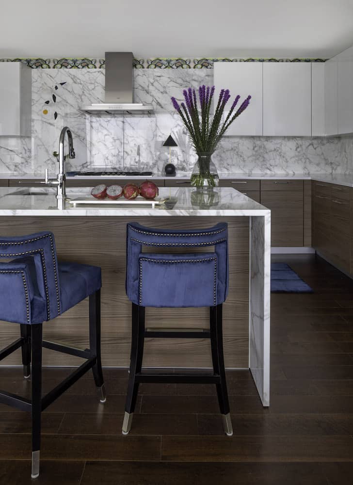 Modern kitchen with marble counters and blue velvet barstools in The River Oaks high-rise