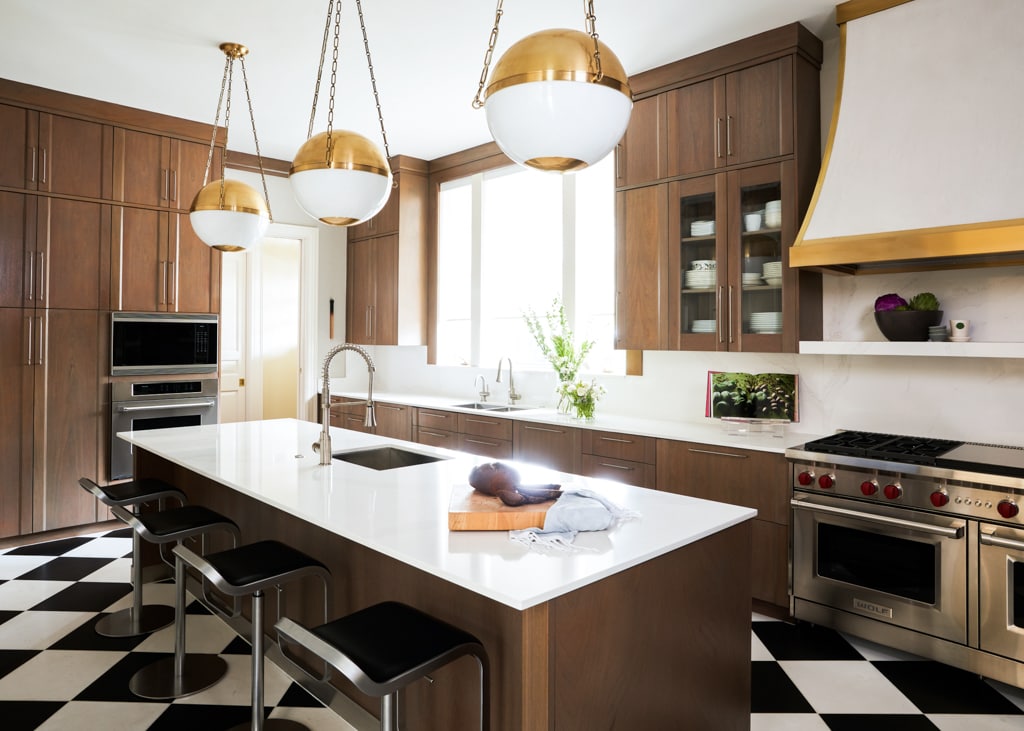 Gold and glass dome pendants from Hudson Valley Lighting hang elegantly over the kitchen island.
